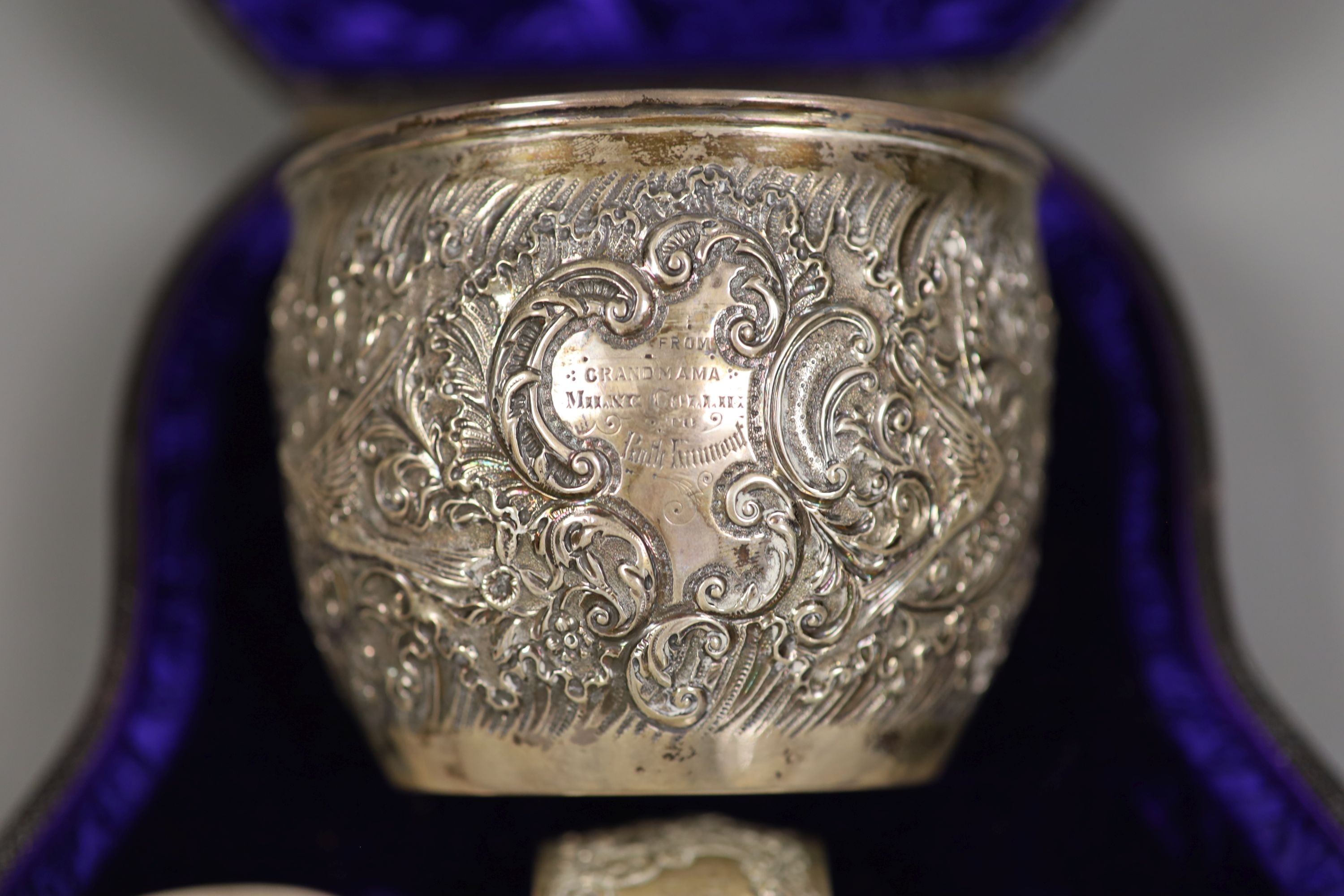 A cased late Victorian embossed silver christening bowl, spoon and napkin ring, Aird & Thomson, Glasgow, 1896, bowl 10.7cm, 7.5oz.